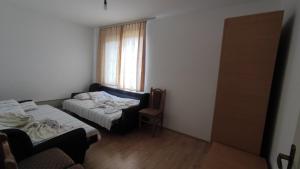 a room with two beds and a chair and a window at Apartment Pavlovic in Soko Banja