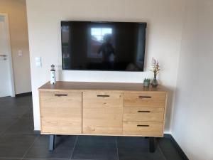 a flat screen tv on top of a wooden dresser at Dat Ankerhuus Timmel in Großefehn 