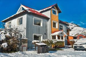 a house in the snow with a car in front at Aguila Mora Aparts in El Chalten