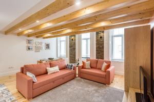 a living room with two pink couches and a tv at Hopstays Oporto Tiles 2 - City Center Duplex in Porto