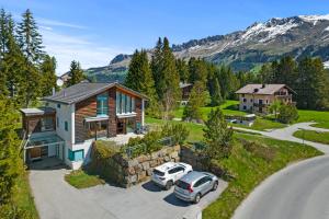 a house with two cars parked in a driveway at Golden Peaks Ferienhaus Valbella-Lenzerheide in Valbella