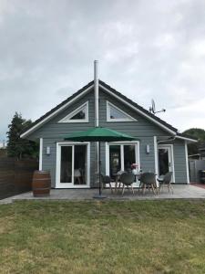 a house with a table with chairs and an umbrella at Wellenzauber - Haus 19 in Grömitz