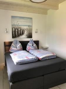 two pillows on a bed with a painting on the wall at Wellenzauber - Haus 19 in Grömitz