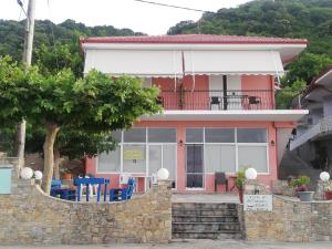 a red house with blue chairs in front of it at Eleni Antonouli Rooms in Kokkino Nero