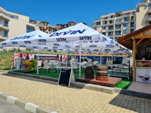 um restaurante com mesas e cadeiras debaixo de um guarda-sol em MitProt Panorama Bay 2 luks apartment ap.73 em Sveti Vlas