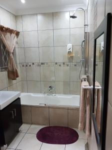 y baño con bañera, lavabo y espejo. en The Fairlands Hideout en Johannesburgo