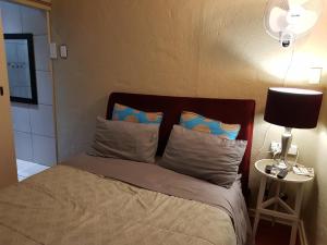 1 cama en un dormitorio con lámpara y almohadas en The Fairlands Hideout en Johannesburgo
