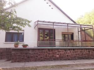 a house with glass windows and a brick wall at Rozmaring Apartman Zánka in Zánka