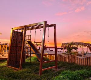 a playground with a swing and a sunset in the background at Maracol Bungalows Vichayito in Vichayito