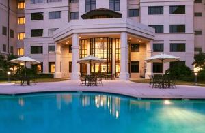 un edificio con piscina frente a un edificio en The Cook Hotel & Conference Center en Baton Rouge