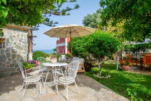 um pátio com uma mesa, cadeiras e um guarda-sol em Alavastros Maisonettes Near 3 sandy beaches em Vasilikos