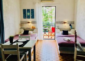 a room with two beds and a table and a balcony at Amazona in Agia Pelagia