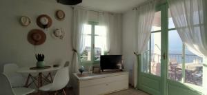 ein Wohnzimmer mit einem TV und einem Balkon in der Unterkunft Paperboat apartment in Afytos