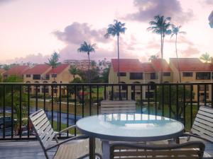 a table and chairs on a balcony with palm trees at BV103 - Amazing Oceanfront Condo steps from beach in Humacao