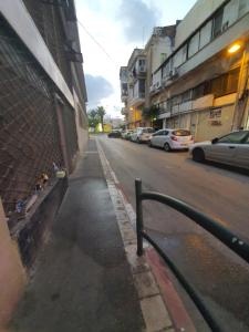 una strada con auto parcheggiate sul lato di un edificio di Laila's studio a Haifa