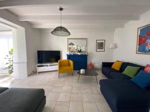 a living room with a blue couch and a tv at Maisons Les Gites de l'Odet in Clohars-Fouesnant