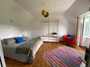 a bedroom with a bed and a red chair at Maisons Les Gites de l'Odet in Clohars-Fouesnant