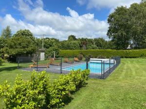 a swimming pool in a yard with benches around it at Maisons Les Gites de l'Odet in Clohars-Fouesnant