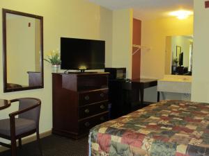 a hotel room with a bed and a desk and a television at First Western Inn - Fairmont City in Fairmont City