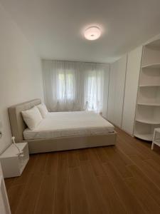 Ein Schlafzimmer mit einem Bett, weißen Vorhängen und Holzboden in der Unterkunft Esperia 1 Piscina e Parcheggio in Caorle