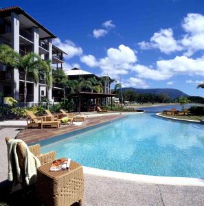 a swimming pool with wicker chairs next to a building at Blue Lagoon Resort in Trinity Beach