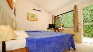 Un dormitorio con una cama azul y una ventana en Pousada El Parador, en Búzios