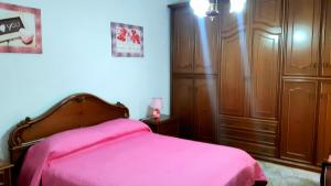 um quarto com uma cama rosa e armários de madeira em Mare&Monti II em Telti