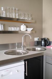 eine Küche mit einem Waschbecken und Gläsern auf Regalen in der Unterkunft THE PARLIAMENT FLATS in Brüssel