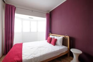 Schlafzimmer mit lila Wänden und einem Bett mit roten Kissen in der Unterkunft THE PARLIAMENT FLATS in Brüssel