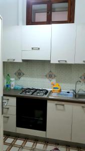 uma cozinha com armários brancos e um forno com placa de fogão em Mare&Monti II em Telti
