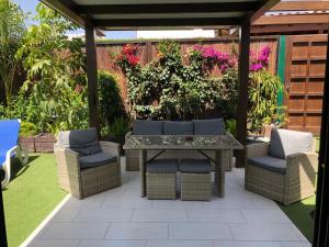 een patio met een tafel, stoelen en bloemen bij Bungalow Portos with amazing privet garden in Playa del Inglés