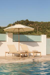 an umbrella and chairs next to a swimming pool at Peratzada in Tsilivi