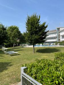 ein Park mit Bänken, einem Baum und einem Gebäude in der Unterkunft Esperia 1 Piscina e Parcheggio in Caorle