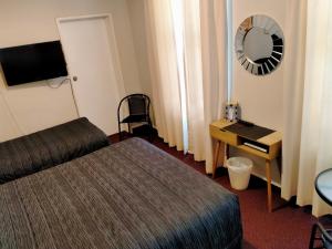 a hotel room with a bed and a desk and a mirror at Masonic Hotel in Palmerston North