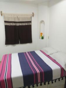 ein Schlafzimmer mit einem Bett mit gestreifter Decke in der Unterkunft Loreto La Regional in Loreto