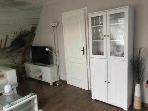a living room with a white cabinet and a tv at Capt'n Eike in Westerdeichstrich