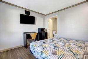 a bedroom with a bed and a desk with a television at Motel 6-Red Bluff, CA in Red Bluff