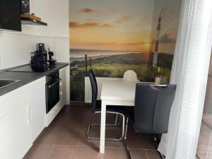 a kitchen with a table and a painting of a beach at Capt'n Eike in Westerdeichstrich