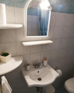 a bathroom with a white sink and a mirror at Paros Iliahtides Apartments near Golden Beach in Márpissa