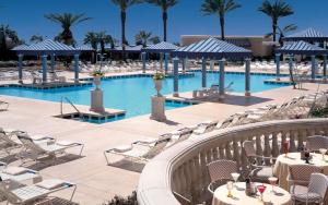 uma piscina de resort com mesas, cadeiras e palmeiras em Beau Rivage Resort & Casino em Biloxi
