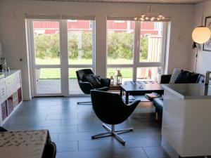 ein Wohnzimmer mit Stühlen, einem Tisch und Glasschiebetüren in der Unterkunft Holiday home Løkken CXVI in Løkken