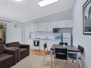 Una cocina y una sala de estar con una mesa y un sofá. en Surfside Palms 14, en The Entrance
