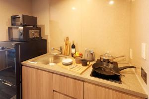 a small kitchen with a sink and a microwave at MONday Apart Premium UENO OKACHIMACHI in Tokyo