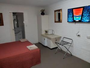 a room with a bed and a chair and a microwave at Colonial Inn Motel in Tamworth