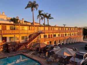 un hotel con piscina, mesas y sombrillas en Seahorse Inn, en Manhattan Beach