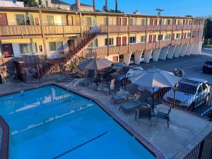 a swimming pool in front of a hotel with umbrellas at Seahorse Inn in Manhattan Beach