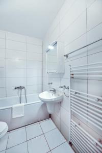 a white bathroom with a sink and a tub and a toilet at Exclusive 7- New Modern Cozy Apartment in Kochani +16 photos