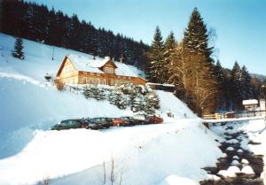 a ski lodge with cars parked in the snow at Lovecká chata in Pec pod Sněžkou