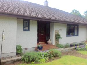 a white house with a red door and flowers at Great location for golf, beach, viewing dolphins. in Fortrose