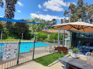 uma cerca com um guarda-chuva ao lado de uma piscina em Bega Southtown Motor Inn em Bega